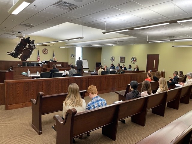 PHOTO OF A COURT ROOM FROM BACK OF THE COURTROOM