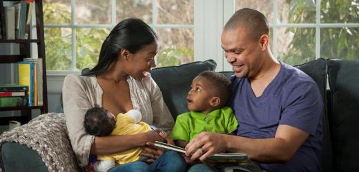 A mother and father sitting on a couch with their two kids.