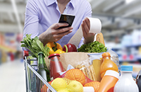 woman shopping for groceries, checking calculator