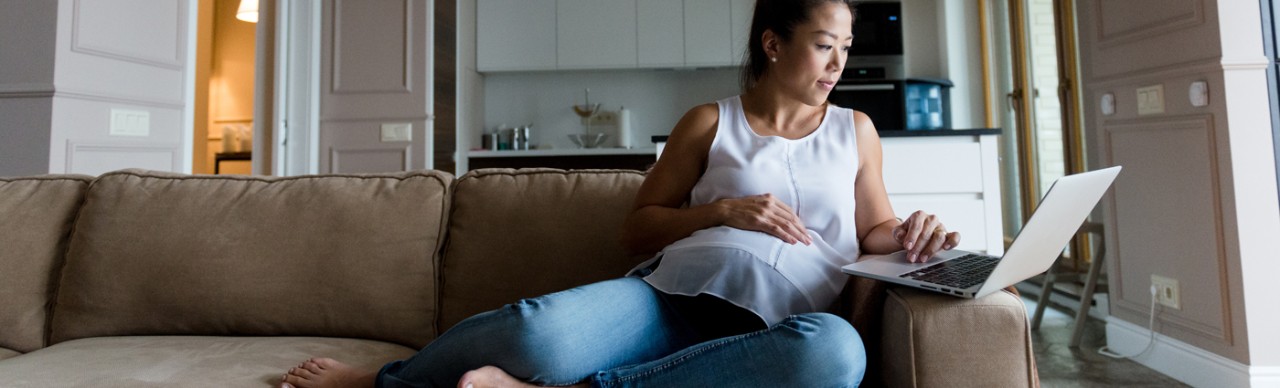 pregnant woman using laptop while on couch