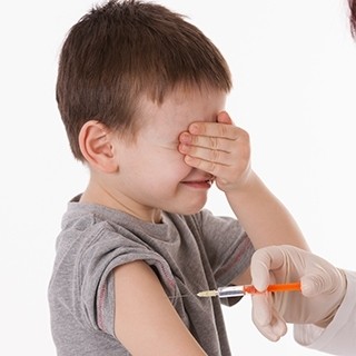 boy covers eyes while getting vaccinated